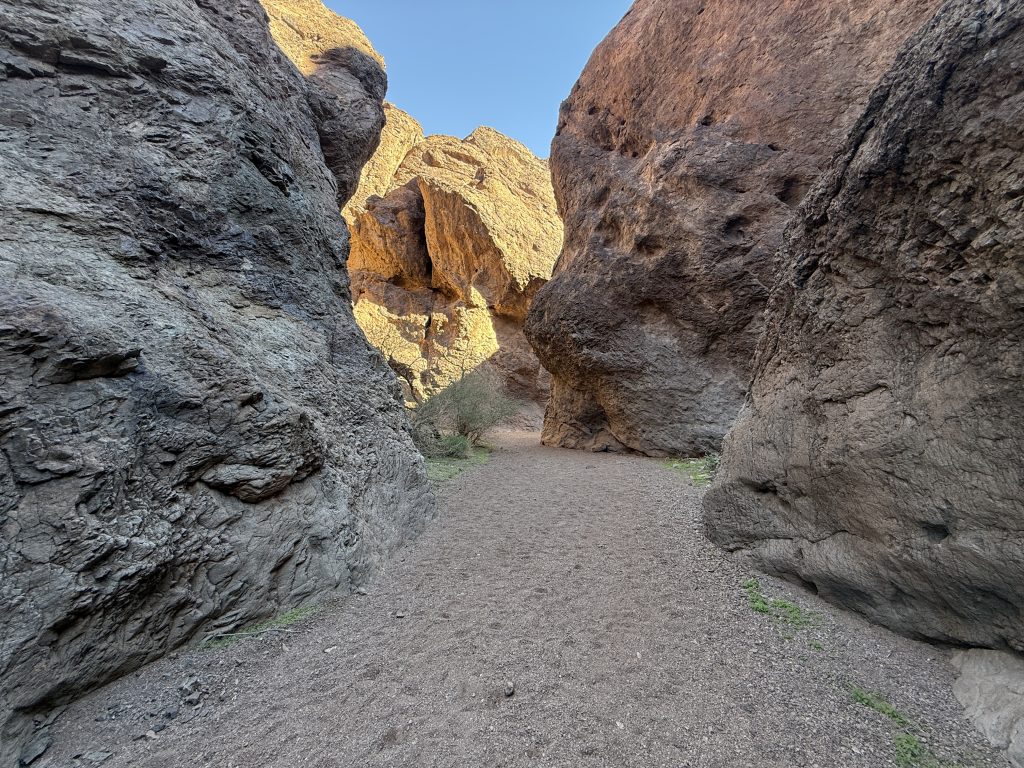 Narrow desert canyon corridor along the Gold Springs Canyon Hot Springs Hike with tall rock walls and sandy trail