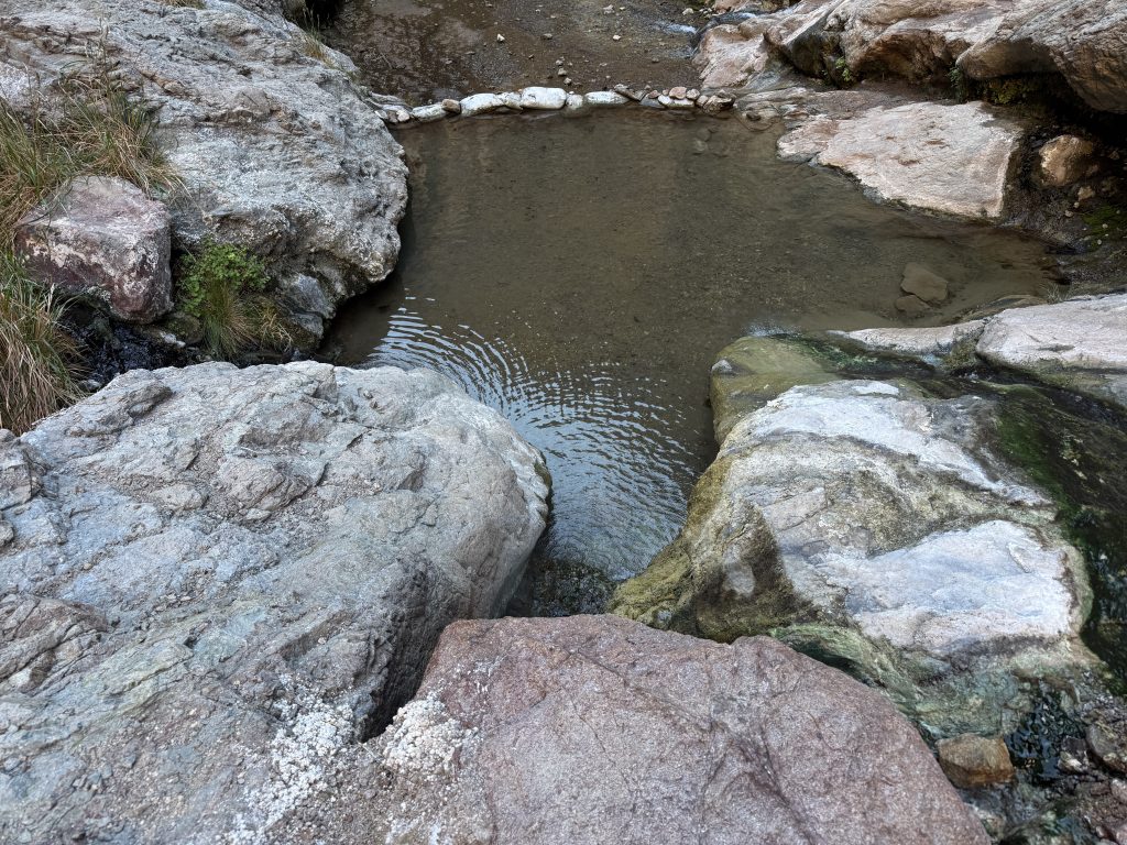 Small natural hot spring pool surrounded by desert rock formations on the Gold Springs Canyon Hot Springs Hike