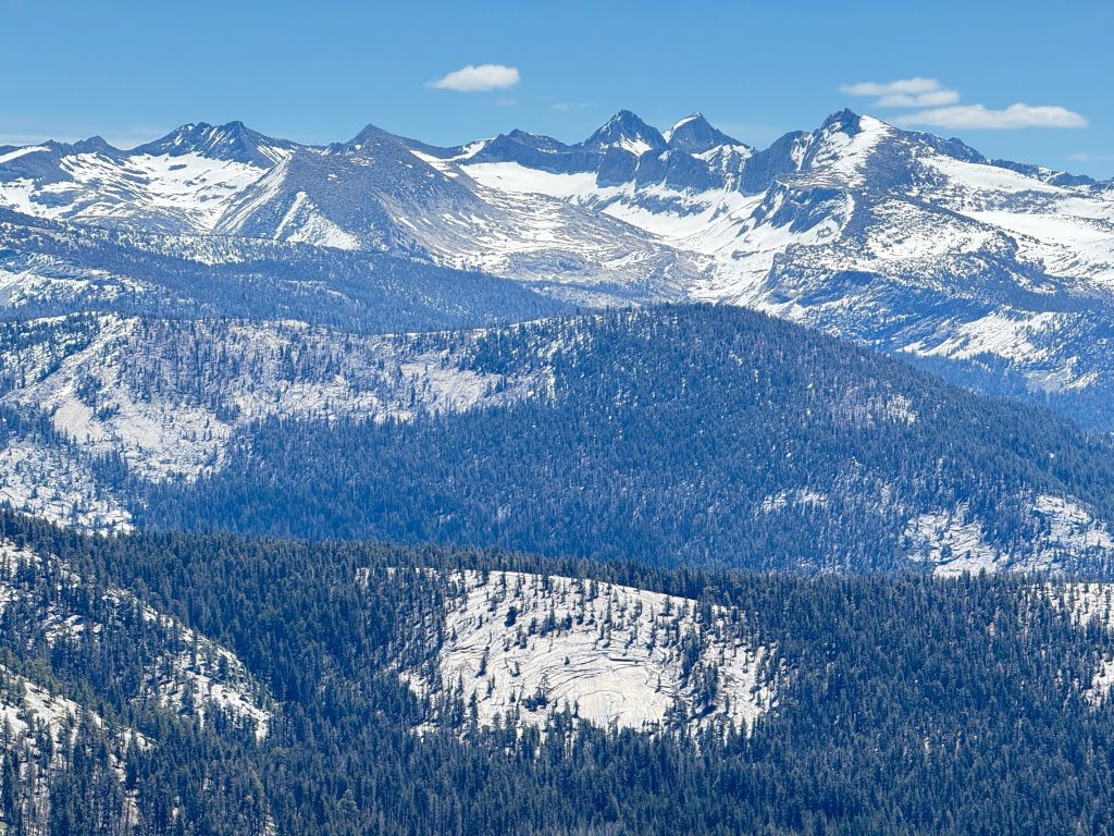 Snow-capped Sierra Nevada peaks viewed from the summit area of Clouds Rest in Yosemite National Park.