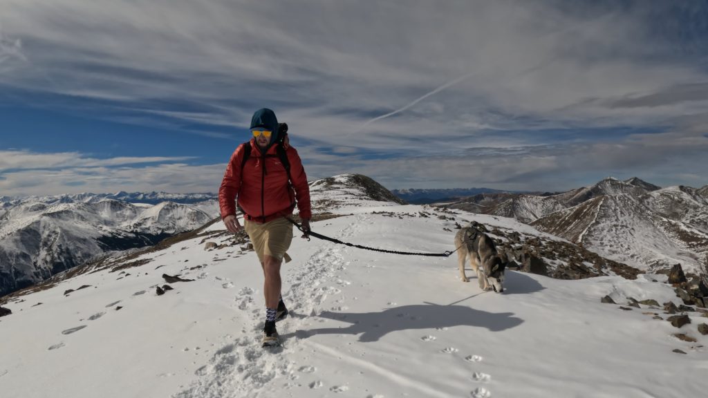 Hiker and dog crossing a snowy section of the Square Top Mountain summit ridge.