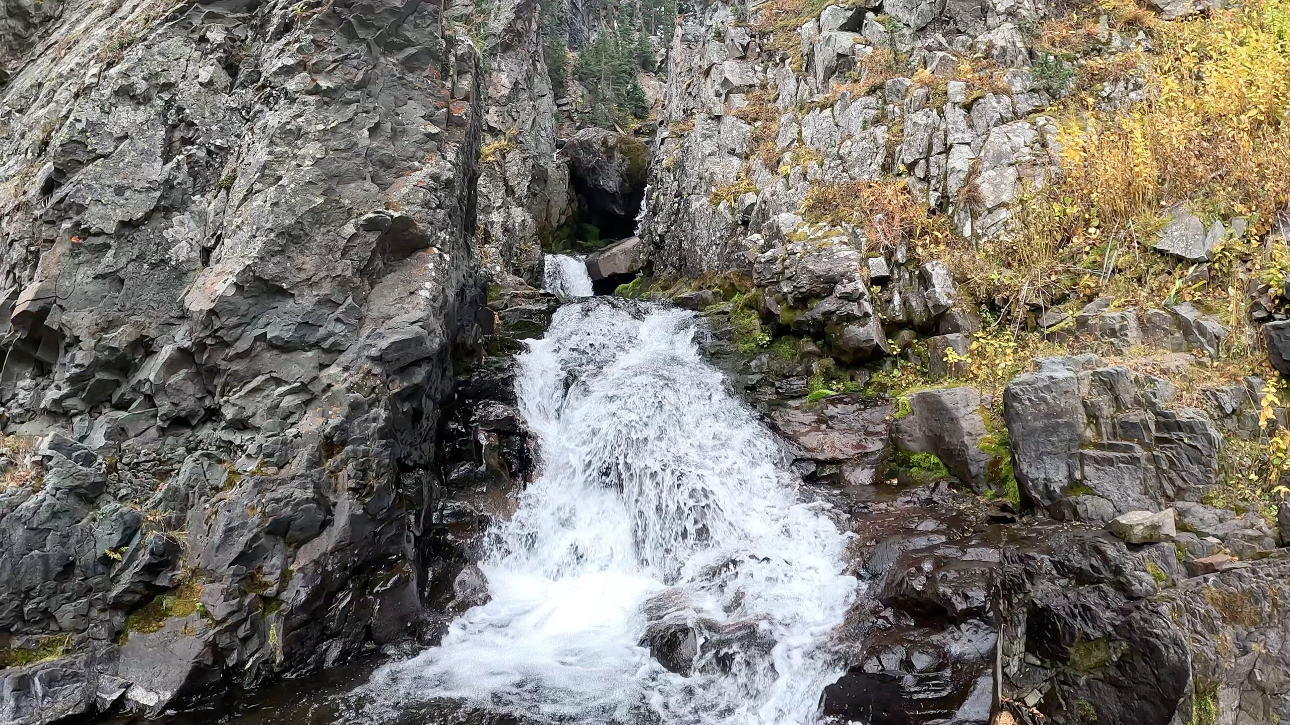 Small mountain waterfall cascading through a rocky canyon along the Blue Lakes Trail in Colorado.