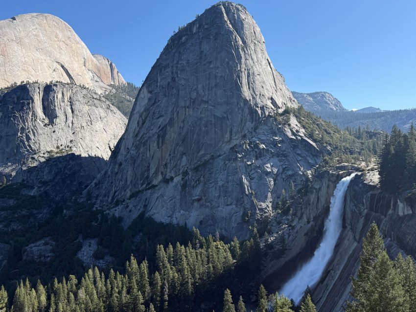 Liberty Cap towering above Nevada Fall in Yosemite National Park beneath a clear blue sky.