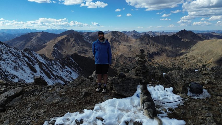 Hiker and dog on the summit of French Mountain with panoramic views of the Sawatch Range and surrounding Colorado 13ers